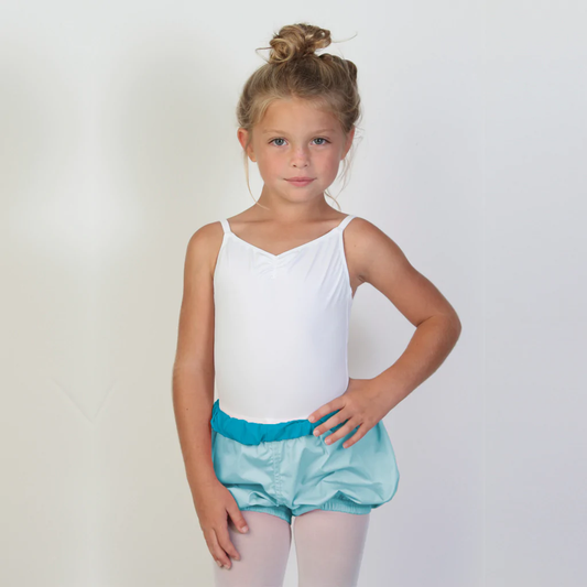 A young ballerina wears light blue trash-bag style shorts with a dark teal waistband.