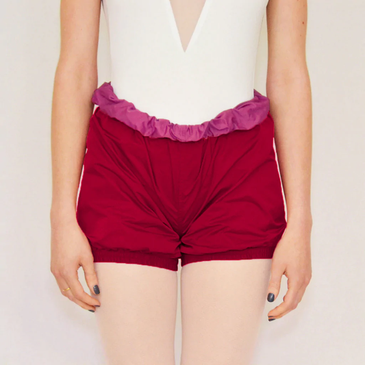 A dancer wears rose red trash-bag style shorts with a fuchsia waistband.